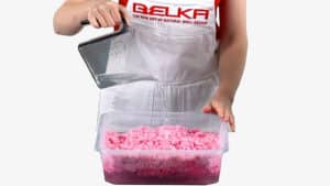 A woman pours water into a container with pink Belka wallpaper.