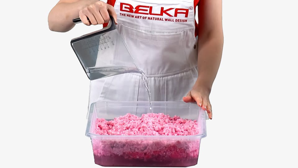 A woman pours water into a container with pink Belka wallpaper.