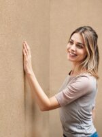 Belka Y2501 Tapete in Sundial Beige an Wohnzimmerwand – moderne, selbstklebende Baumwolltapete mit natürlicher Textur, ideal für umweltfreundliche, warme und schallgedämmte Raumgestaltung.