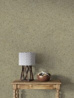 Wüstentaupenfarbene Belka Y2504 Tapete, aufgetragen auf eine moderne Wohnzimmerwand. Die warme, erdige Textur harmoniert mit minimalistischen Möbeln in Grau und Weiß, schafft eine gemütliche, stilvolle Atmosphäre. Im Licht schimmert die Tapete sanft und betont die natürliche Eleganz des Raumes