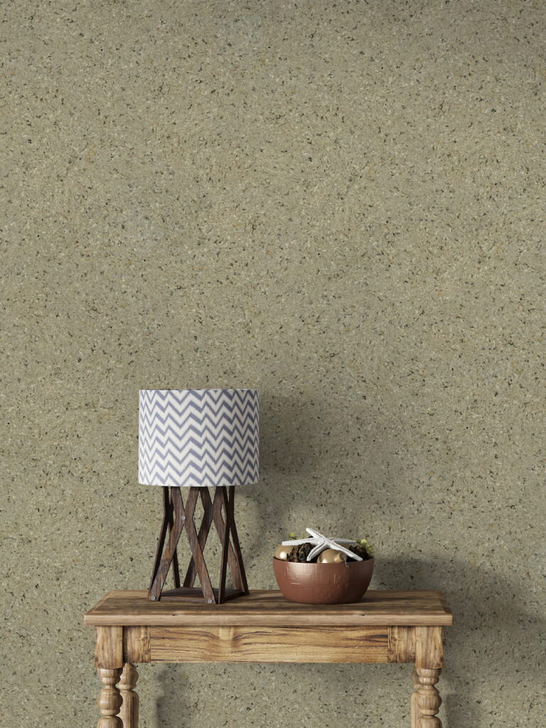 Wüstentaupenfarbene Belka Y2504 Tapete, aufgetragen auf eine moderne Wohnzimmerwand. Die warme, erdige Textur harmoniert mit minimalistischen Möbeln in Grau und Weiß, schafft eine gemütliche, stilvolle Atmosphäre. Im Licht schimmert die Tapete sanft und betont die natürliche Eleganz des Raumes