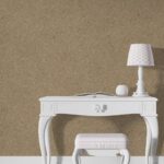 Belka Y2505 Tapete Caramelized auf einer modernen Wohnzimmerwand. Die warme, strukturierte Oberfläche harmoniert mit Holz- und Cremetönen, schafft eine gemütliche, elegante Atmosphäre. Im Licht schimmert die Tapete sanft und betont natürliche Wärme.