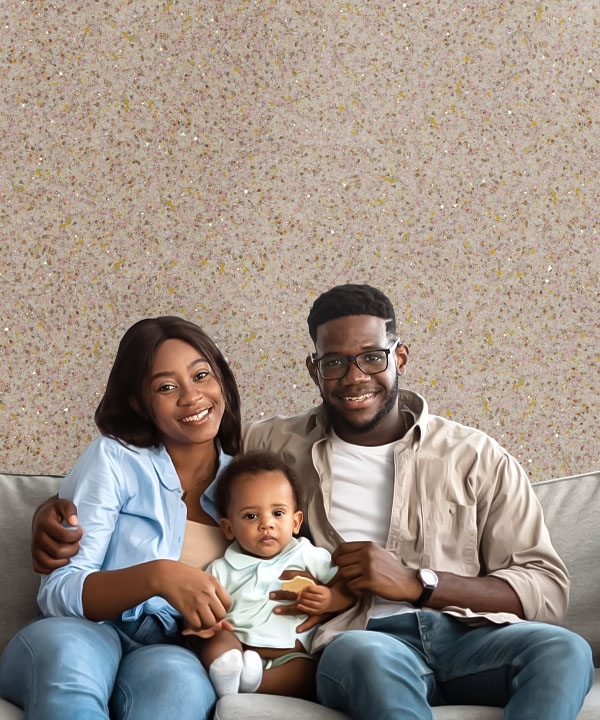 A happy black family with a baby sits on a sofa in the living room. The walls are covered with Belka light brown wall paint.