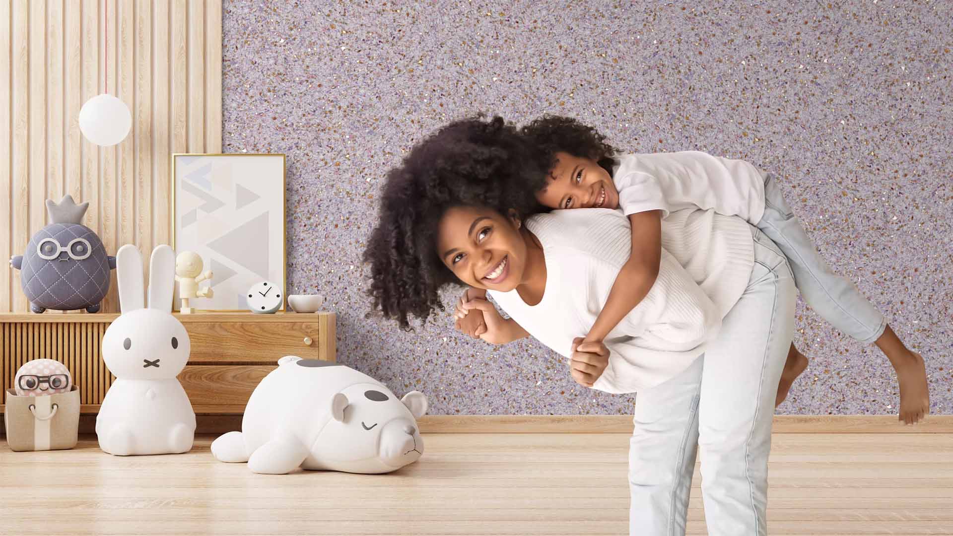 A happy black mother and her son are in a baby room. The walls are covered with Belka lilac wall paint and Lumika gold.